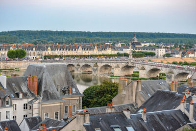 Arch bridge over river against buildings in city