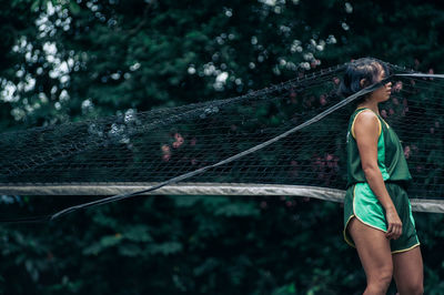 Midsection of young woman against trees