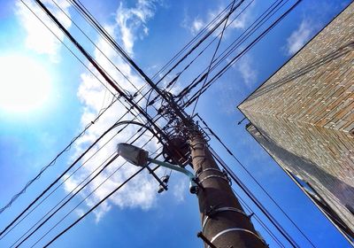 Low angle view of electricity pylon against cloudy sky