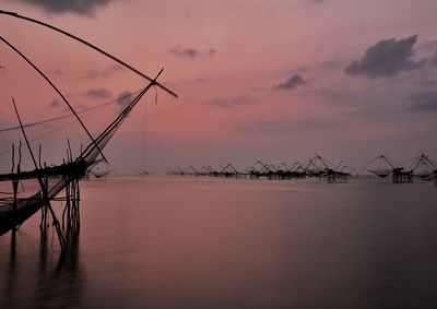 Cranes against sky during sunset