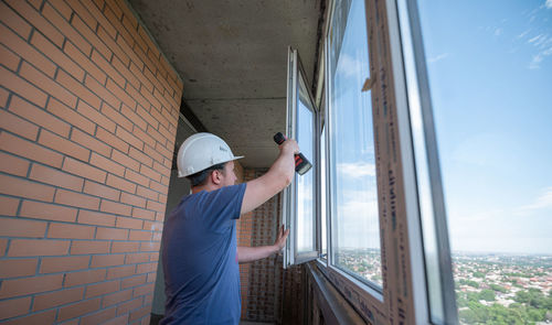 Man standing by window at construction site
