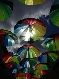 Low angle view of multi colored umbrellas hanging against sky