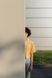 Woman standing behind wall on sunny day