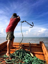 Man fishing by sea against sky