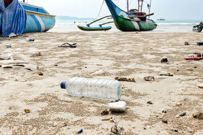 Boats moored on shore at beach against sky