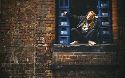 Full length of young woman crouching at window