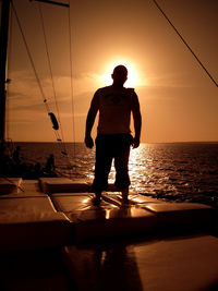 Rear view of silhouette man overlooking calm sea