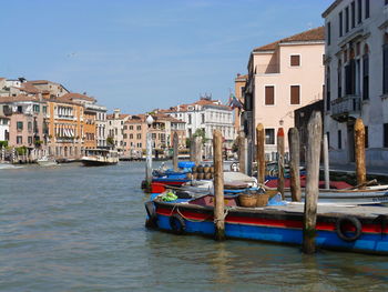 Boats moored in canal amidst buildings in city