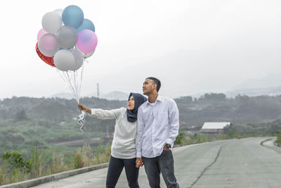 Full length of a man with balloons standing against sky