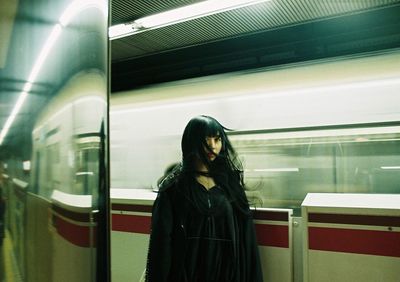 Rear view of woman standing on train at subway station