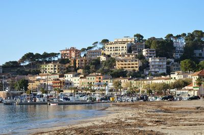 Buildings by sea against clear blue sky