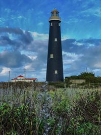 Lighthouse on field against sky