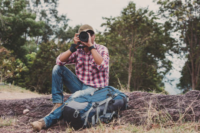 Full length of young man sitting on sunglasses