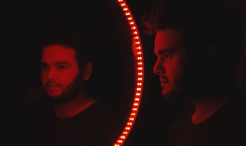 Close-up portrait of young man and woman against black background