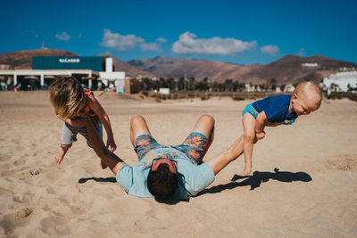 Father and children working out and playing at the beach on sunny day