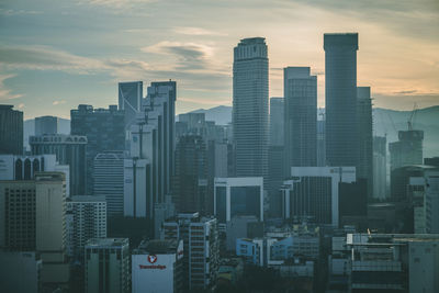 Modern buildings in city against sky during sunset