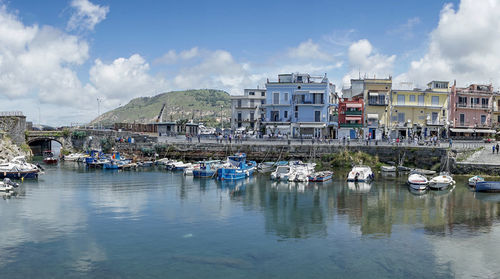 Sailboats moored in harbor against buildings in city