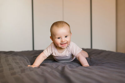 Cute baby is lying on his tummy, leaning on his wrists and laughing