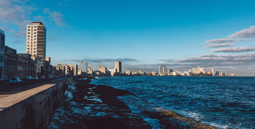 City buildings by sea against sky