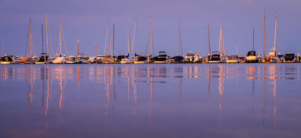 Sailboats moored in harbor against clear sky