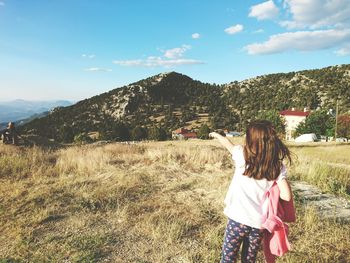 Rear view of girl on mountain against sky