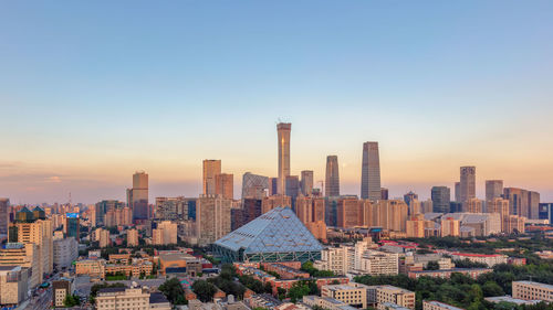 Modern buildings in city against sky during sunset