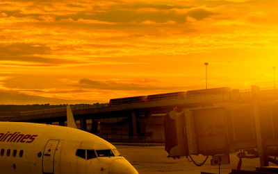 Airplane at airport against orange sky