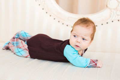 Portrait of cute girl sitting on bed at home