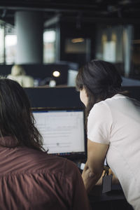 Rear view of it professional with colleague working on laptop in office