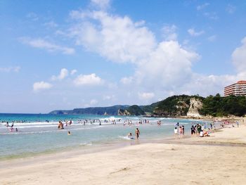 People enjoying at beach against sky