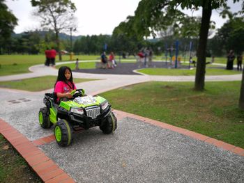 Girl riding beach buggy on footpath at park