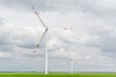 Windmills on field against sky