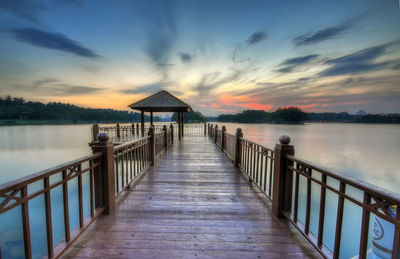 Pier leading to calm lake at sunset