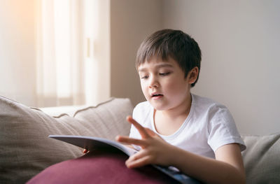 Boy sitting on book at home