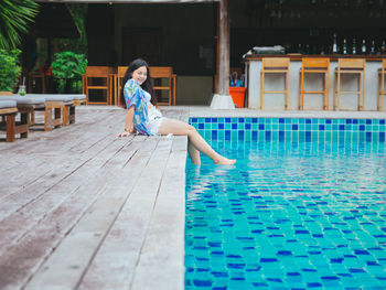 Young asian woman relaxing outdoor beside swimming pool in hotel resort for leisure vacation