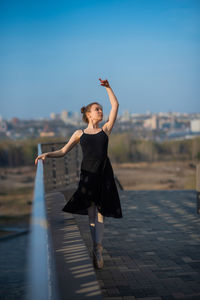 Full length of young woman standing on floor against sky