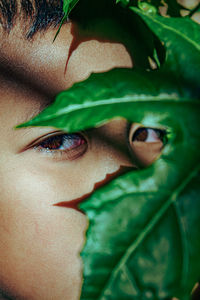 Close-up portrait of woman with green leaves