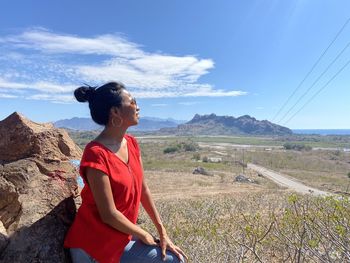 Full length of smiling woman on land against sky