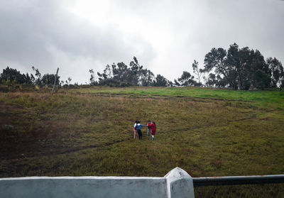 Rear view of men on field against sky