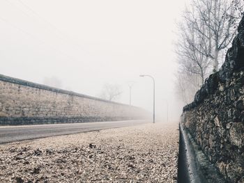 Empty road amidst wall in foggy weather