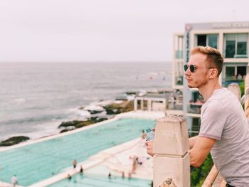 Young man looking at sea against sky