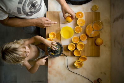 Boy making orange juice with father