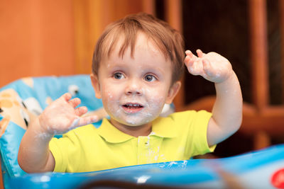 Close-up of baby boy with messy face sitting in high chair