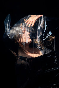 Close-up of hand on glass against black background