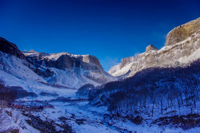 Scenic view of snowcapped mountains against clear blue sky