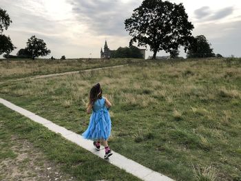 Full length rear view of woman on field against sky