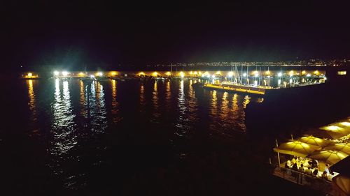 Illuminated bridge over river in city at night