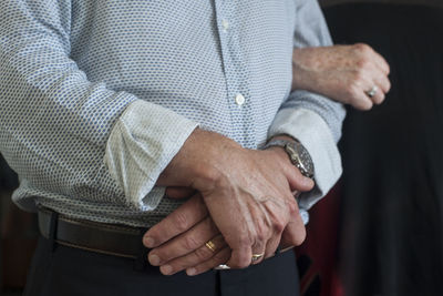 Midsection of man holding hands while standing at home