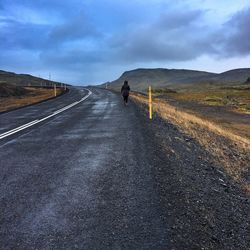 Rear view of people walking on country road