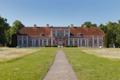 Houses by building against clear blue sky